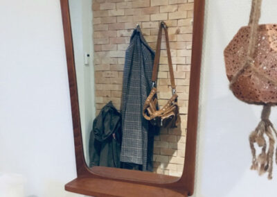 Hallway with jacket and a bag placed on a wall decoration. Mirror and a shelve