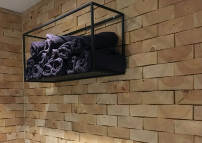 Wooden wall covering of solid pine wood blocks. Shelve mounted on the wall