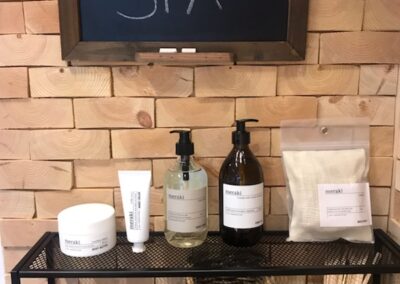 Wooden wall decoration of untreated pine wood blocks. Black shelve with hair products mounted in the wall
