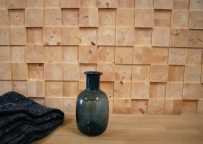 Wooden wall decoration of raw face blocks. Bench with a blanket and a vase