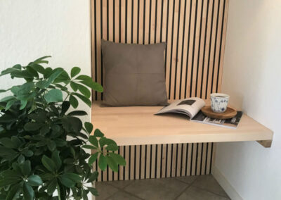 Hall with wall covering of wood. Bench with magazine, pillow and a cup of coffee
