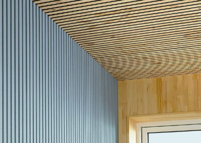 Wooden raw and painted coverings on ceiling and walls in a room with a window