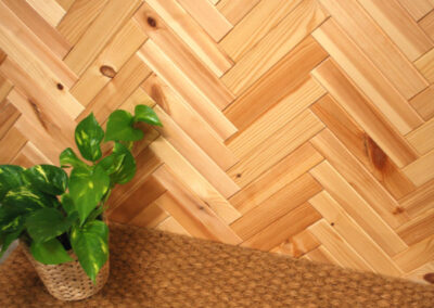 Wooden wall decoration mounted in a herringbone pattern. A flower is placed on a mat.