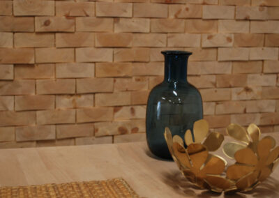 Wooden wall decoration of raw face blocks. A vase and a bowl standing on a table of wood