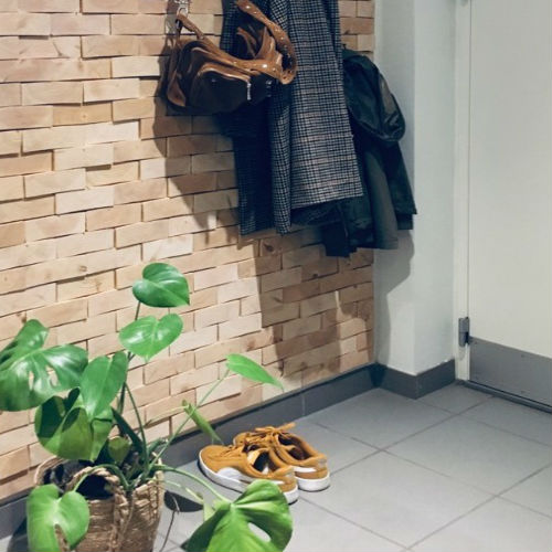 Wall decoration of wood in a hall with shoes, bag, jackets and flower